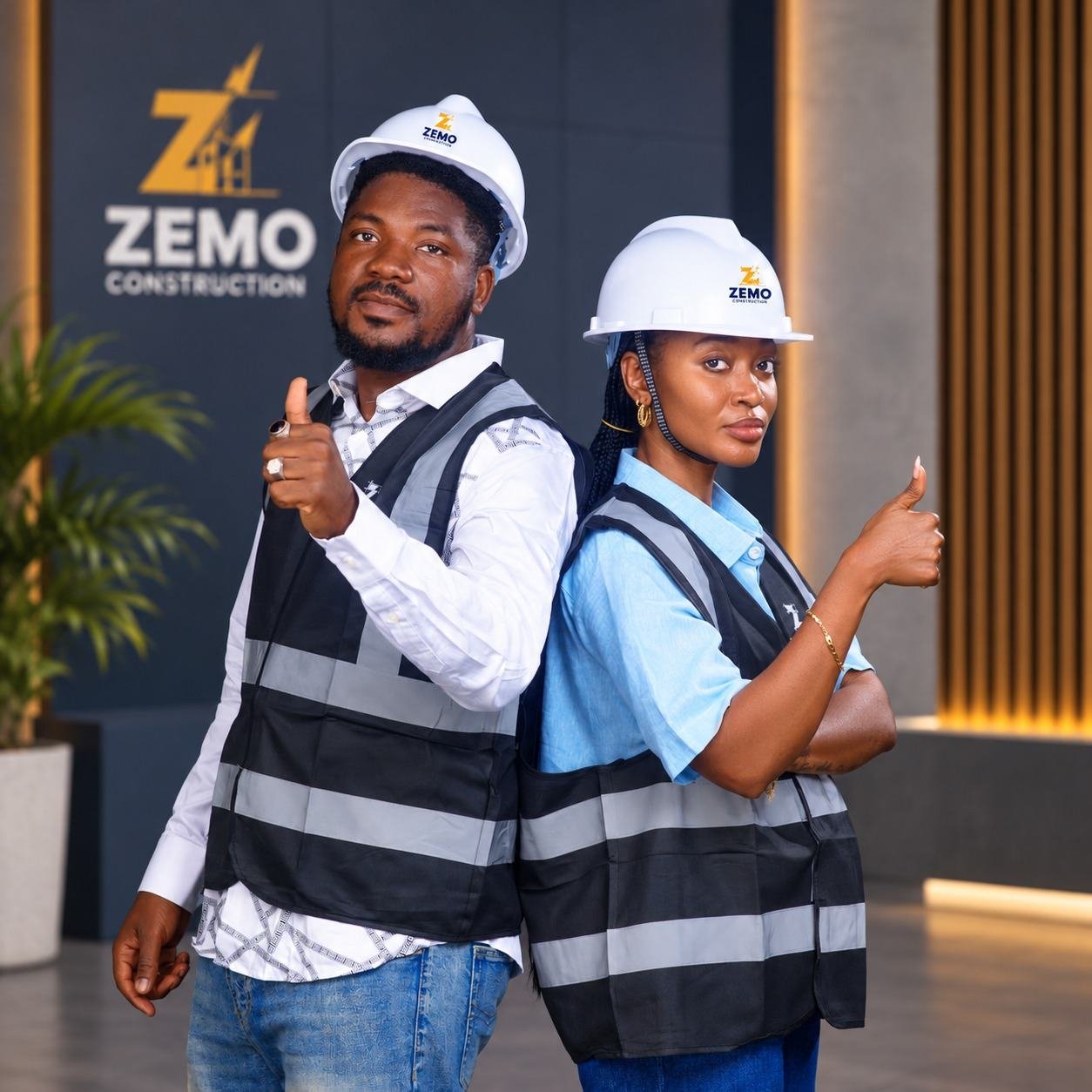Deux membres de l'équipe ZEMO Construction, casque blanc et gilet, pouces levés devant le logo de l'entreprise